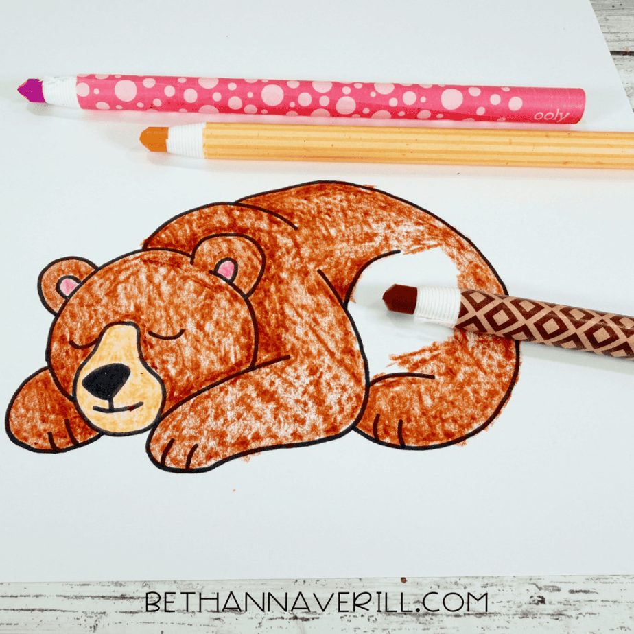 Printed sleeping bear picture being colored brown, tan, pink, and black with colored pencils.