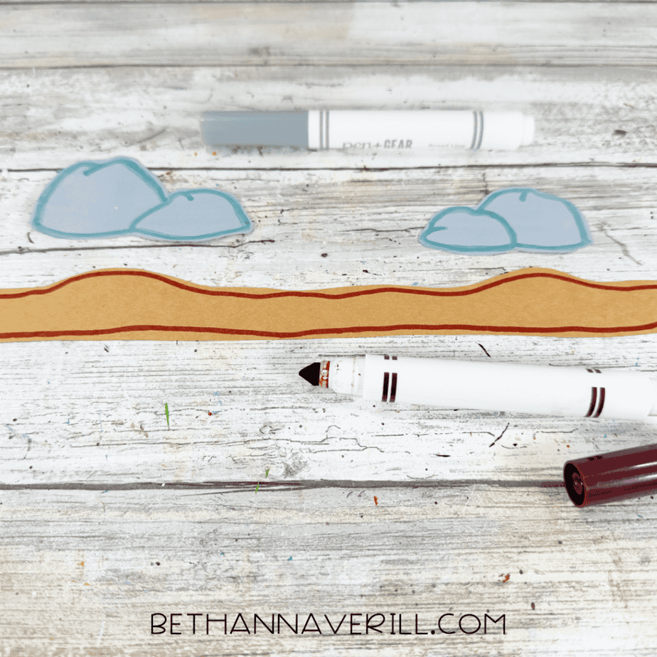 Gray paper rocks outlined in blue and a long brown paper strip outlined and detailed with a dark reddish-brown marker.