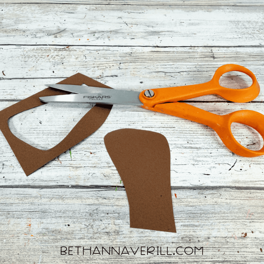 Brown construction paper acorn stem cut out and placed beside orange scissors and leftover paper.