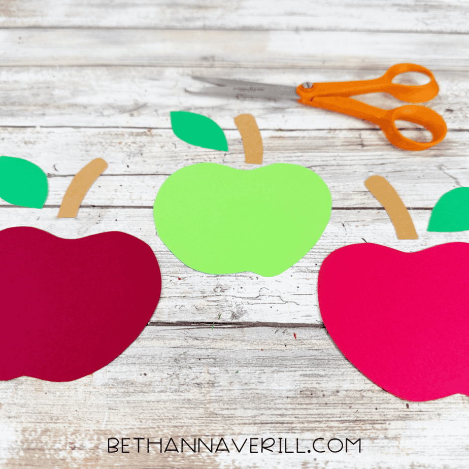 Red, pink, and green paper apples with matching green leaves and tan stems cut from construction paper.