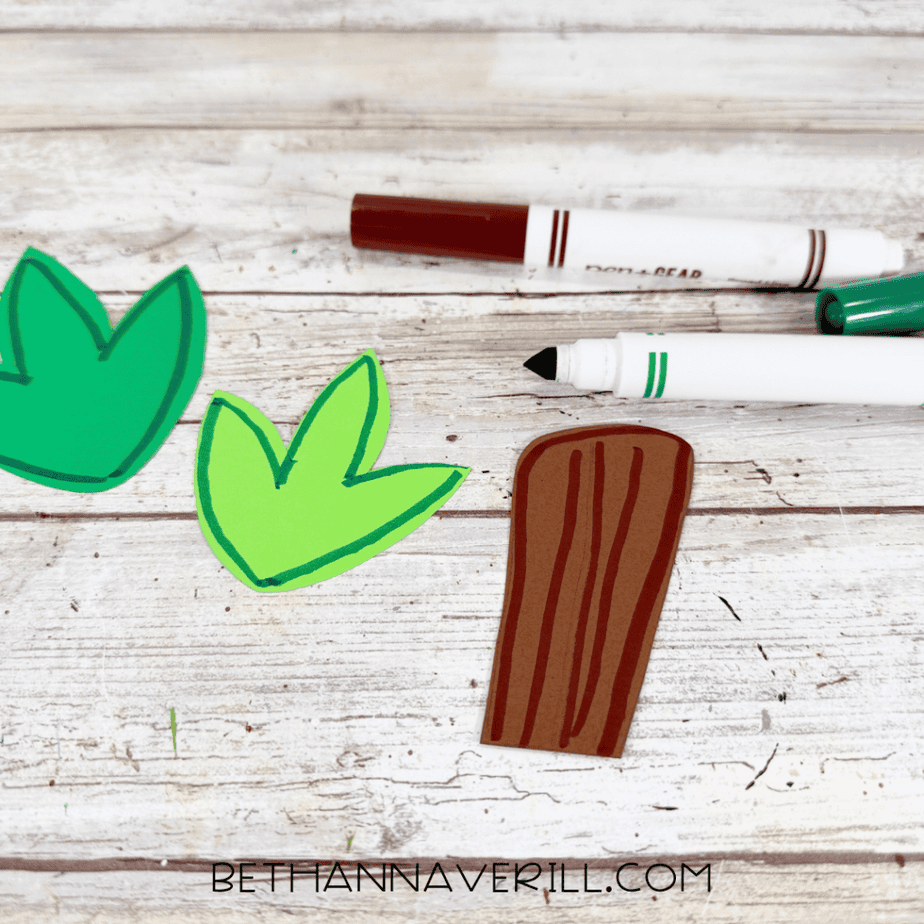 Two green paper leaves and a brown paper stem outlined with markers.