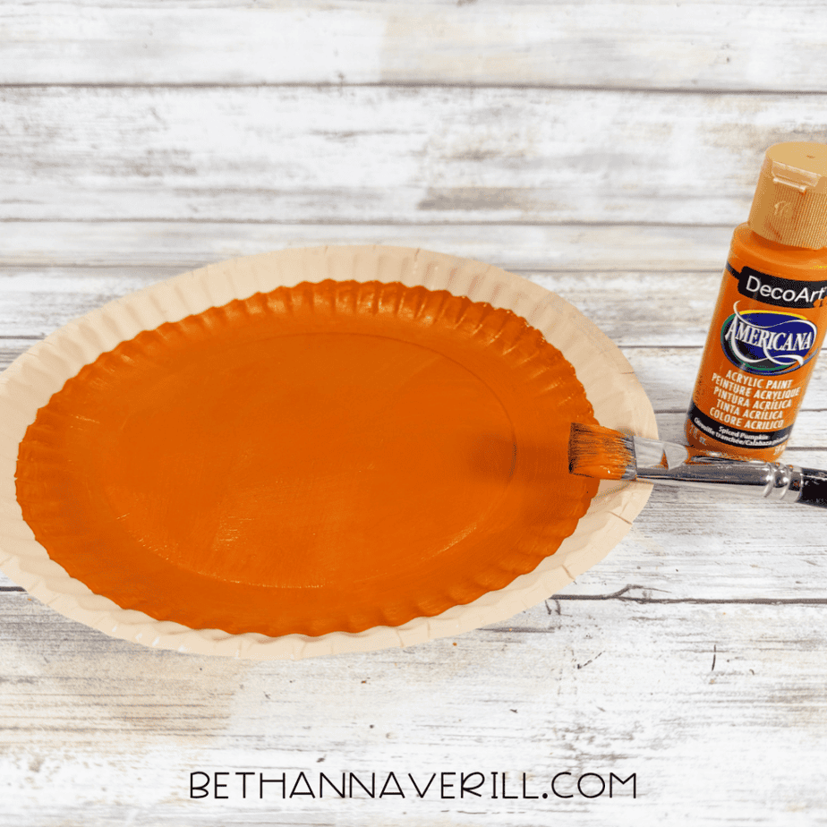 Paper plate painted orange in the center while leaving the outer rim unpainted for the pie crust.
