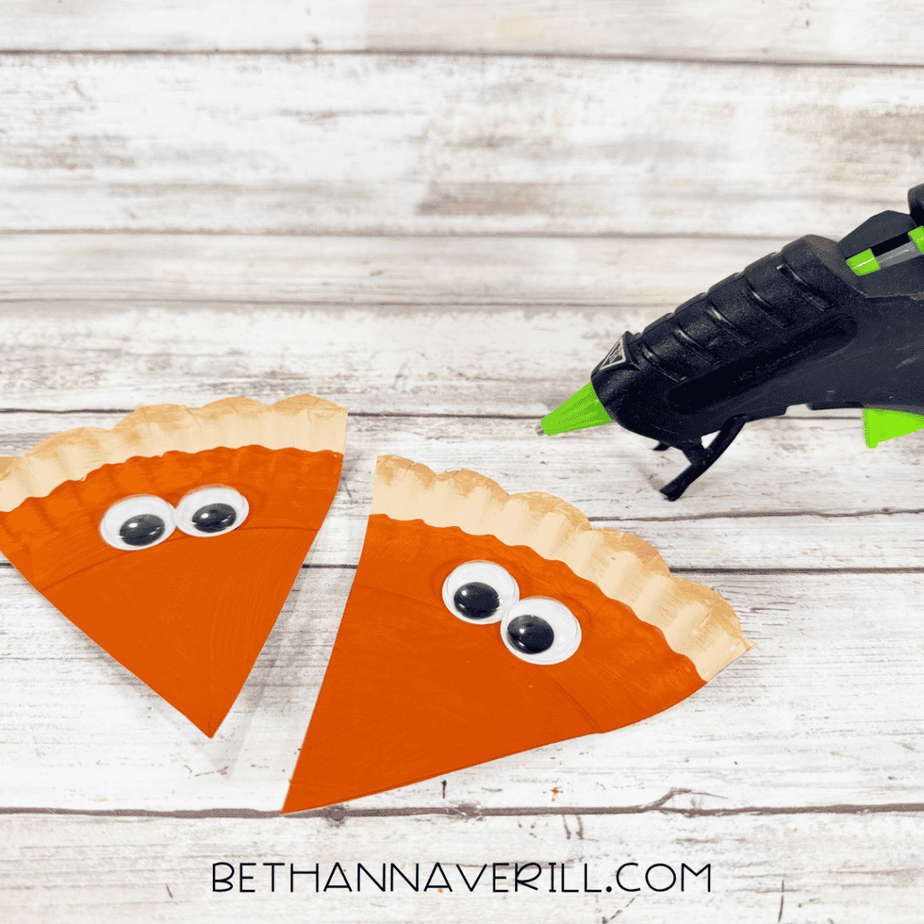 Two pumpkin pie paper plate slices with googly eyes attached near the crust.