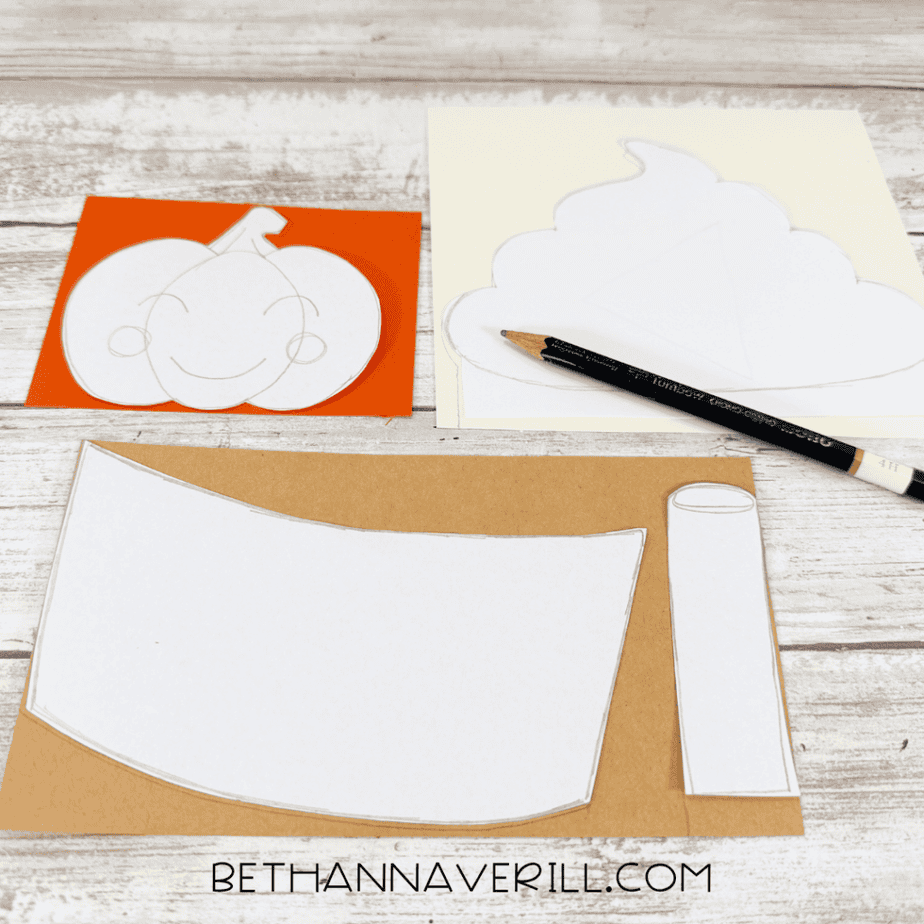 White paper templates traced onto orange, cream, and brown paper with a pencil.
