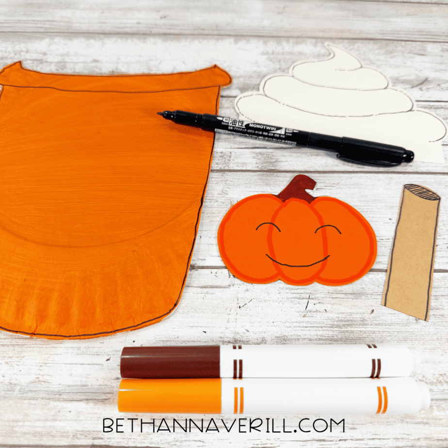 Orange paper plate cup with outlined cream topping, orange pumpkin piece, brown stick, markers, and paint.